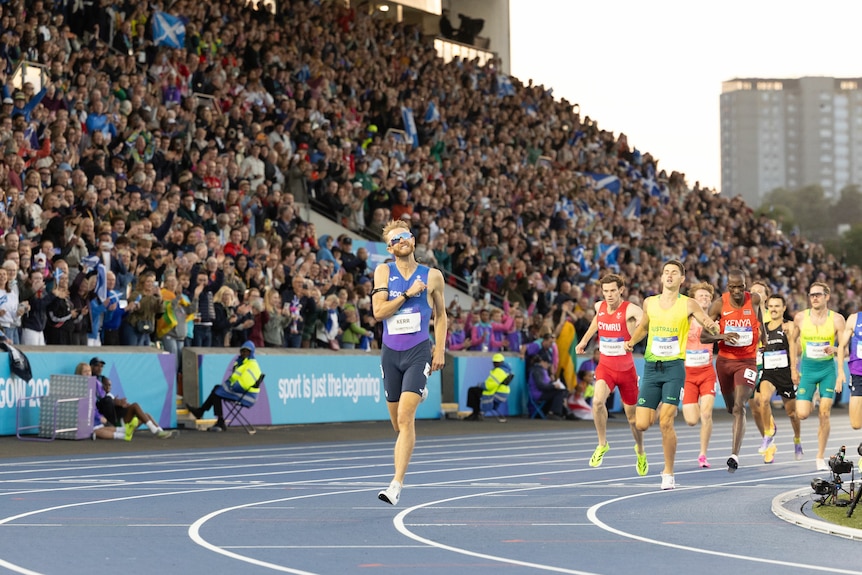 Josh Kerr, in a purple and blue running uniform, out in front of a group of runners as a large crowd watches on.