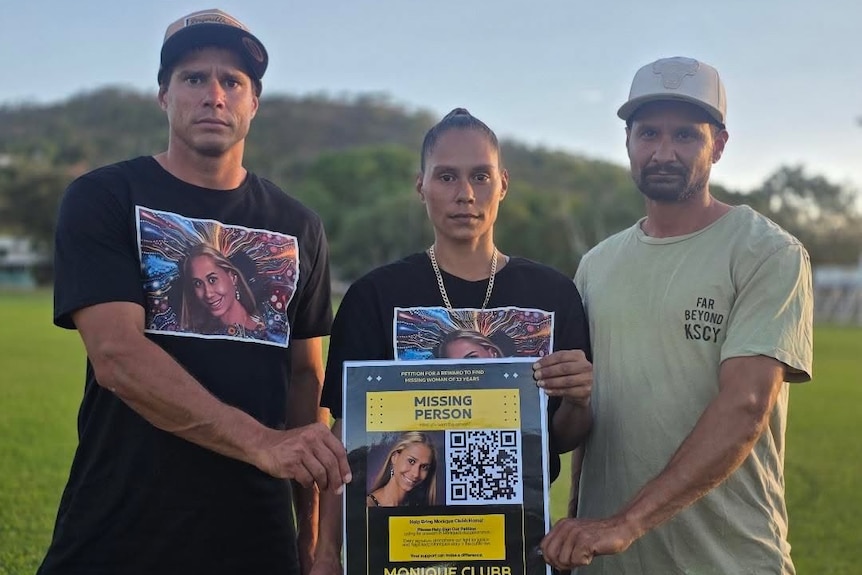 Three siblings wearing matching shirts hold a large black and yellow poster.