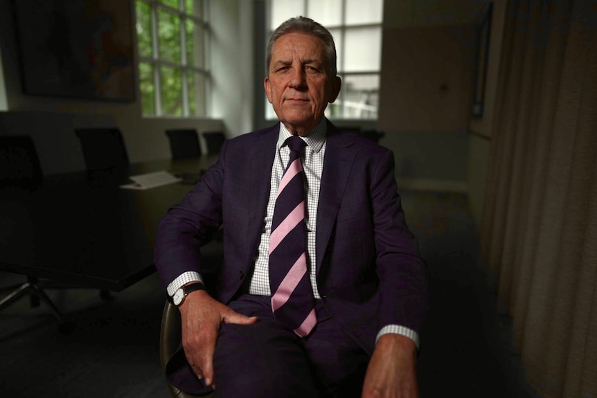 Australian anti-slavery commissioner Chris Evans wearing a suit and tie sitting in a chair.