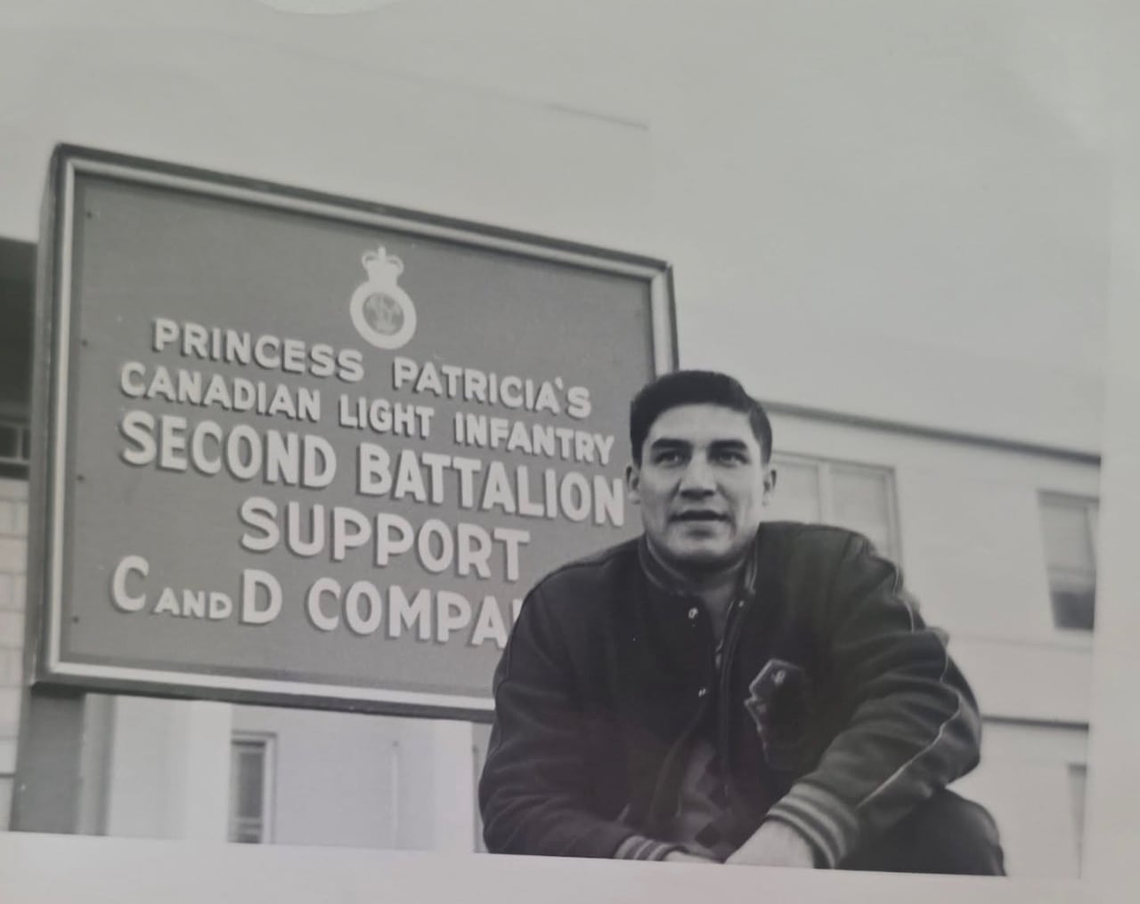 A young man posing in front of a sign that says "Princess Patricia's Canadian Light Infantry"