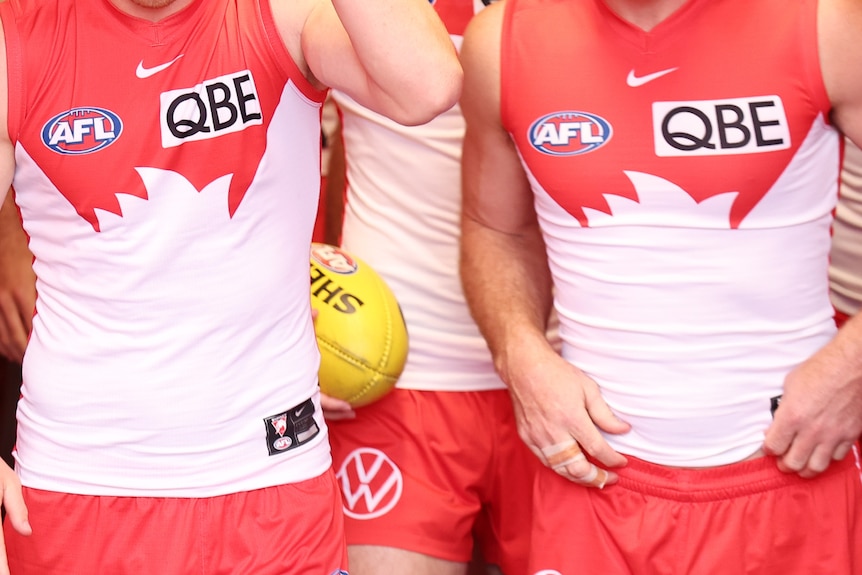 Unidentified Sydney Swans players walk up the tunnel onto an AFL field.