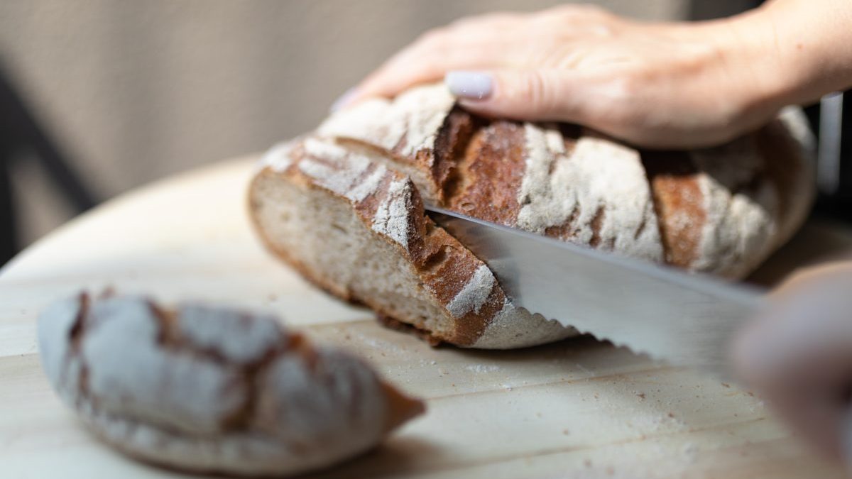 Female Hands cutting bread. - stock photo