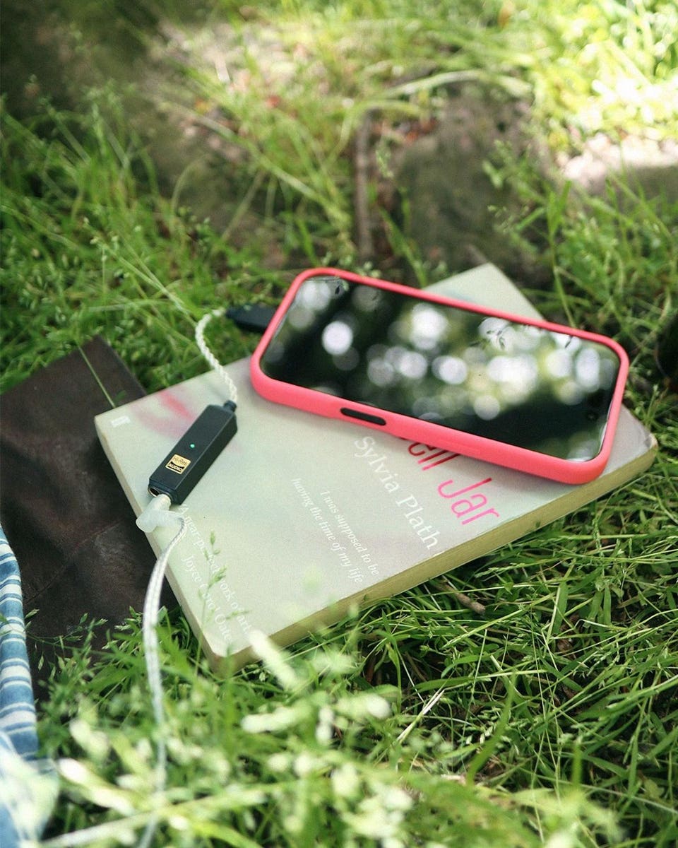 iFi Audio GO link 2 Max on paperback book with smartphone