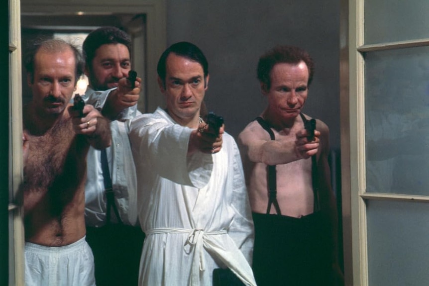 A screenshot of the four leads from Salo, they all point guns