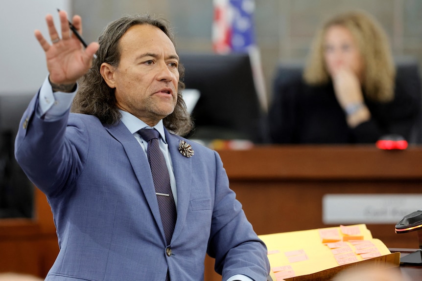 Sanft gestures with one arm outstretched as he makes comments in a courtroom.