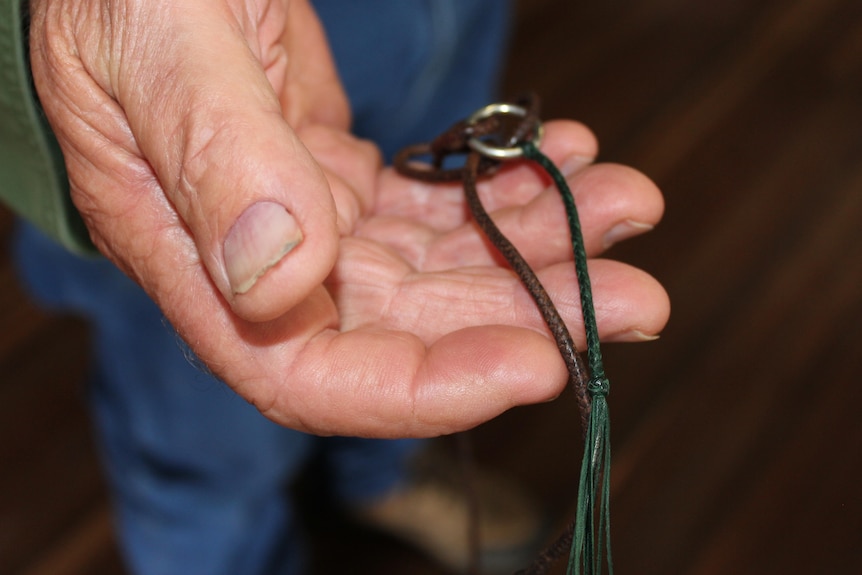 A man's hand holding plaited leather