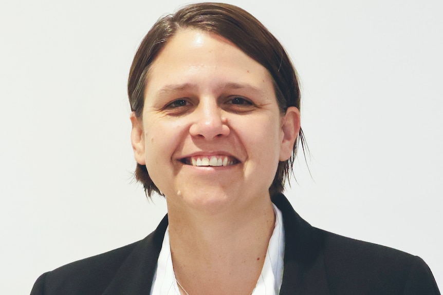 A professional headshot of a woman with short dark hair smiling. 