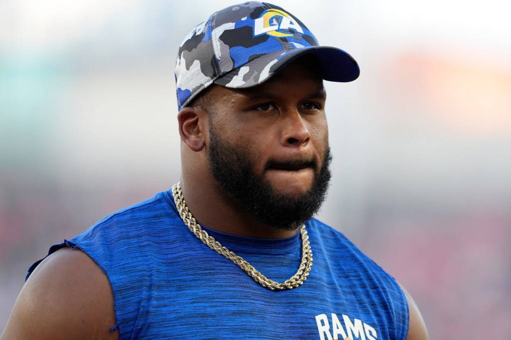 Aaron Donald wearing a Rams hat and blue shirt with a gold chain.