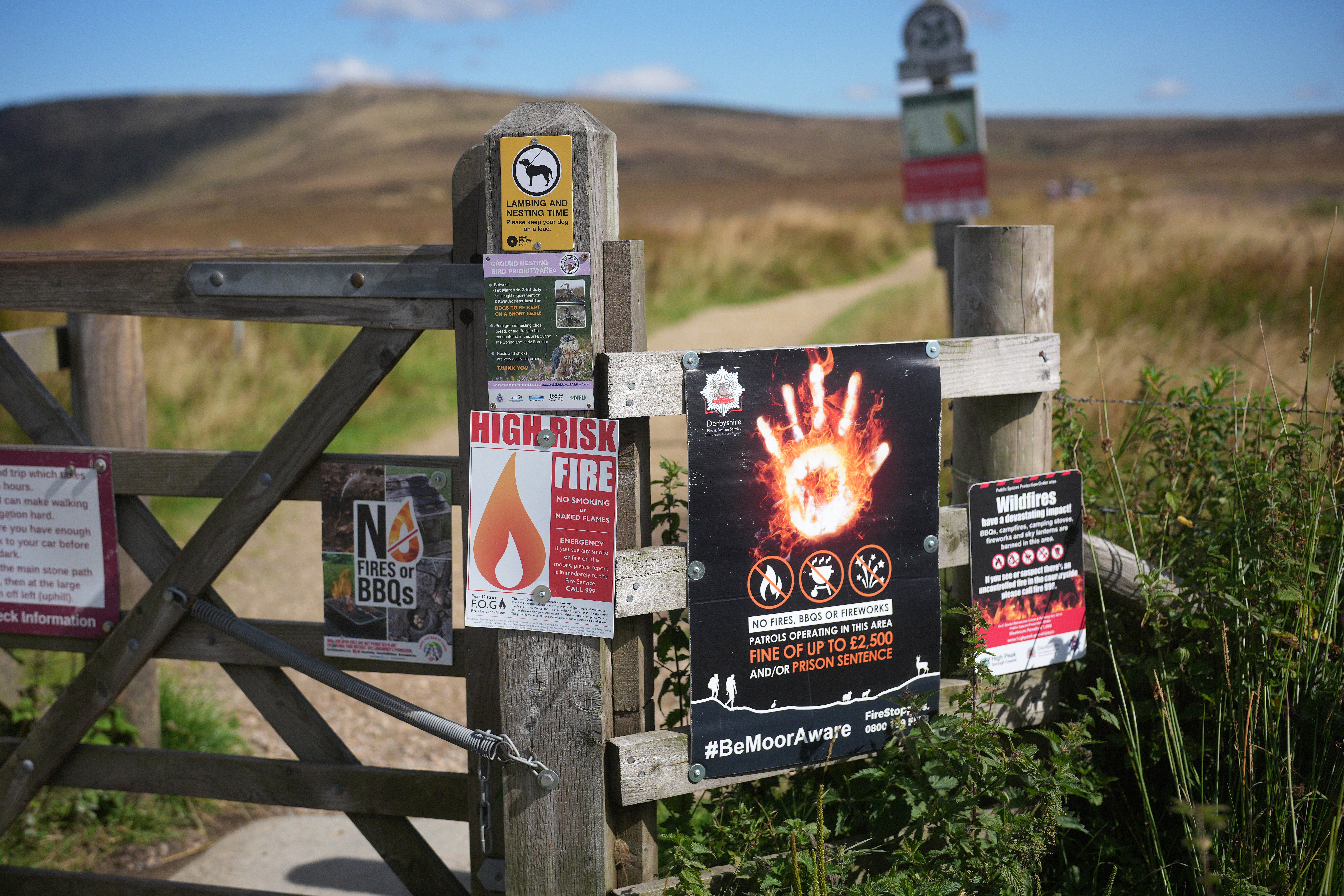 Wildfire warning signs are fixed to a gate on Hope Woodlands Moor in the Peak District