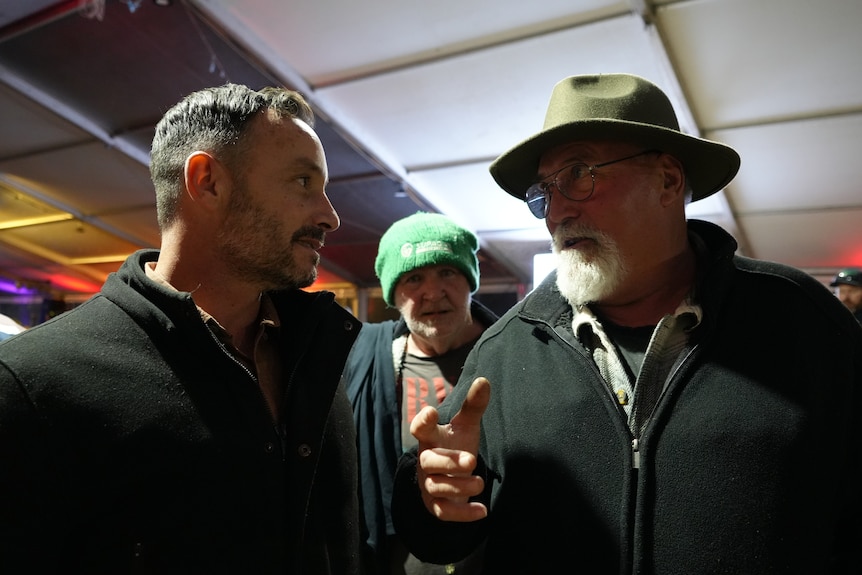 Two men talking to each other under an event tent.
