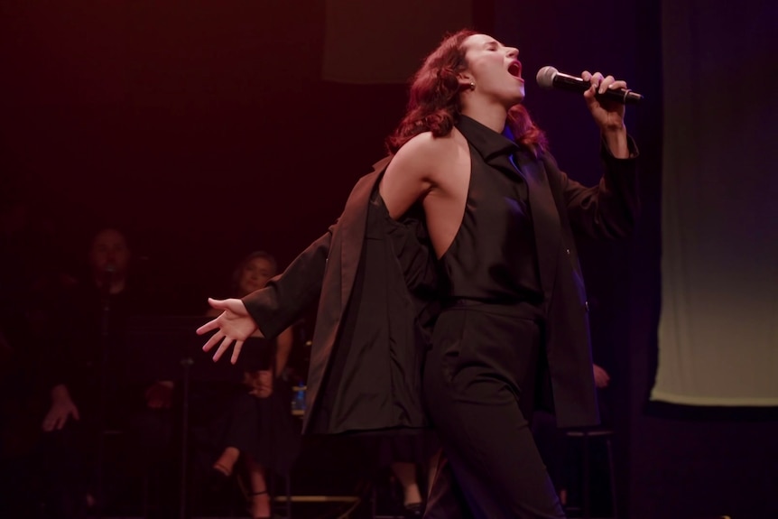 A woman on stage holding a micophone and performing.