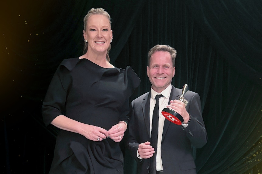 Leigh Sales stands next to Greg Hassall against black background while holding a Logie award.