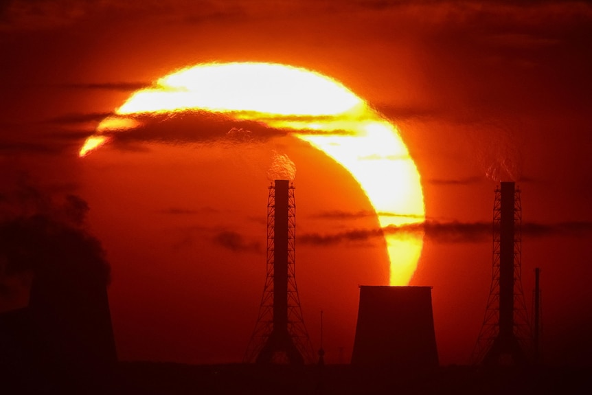 A partial solar eclipse over a power station.