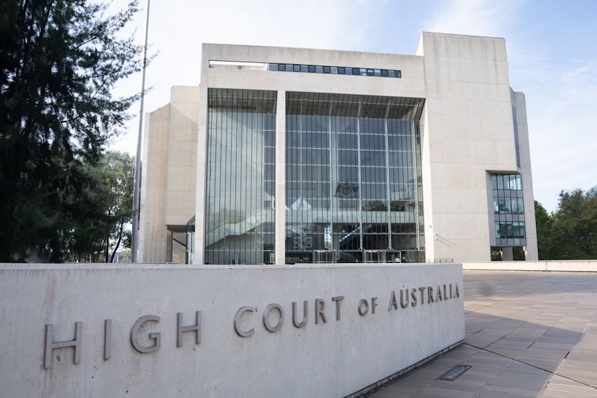 A square building behind a sign saying "High Court of Australia".