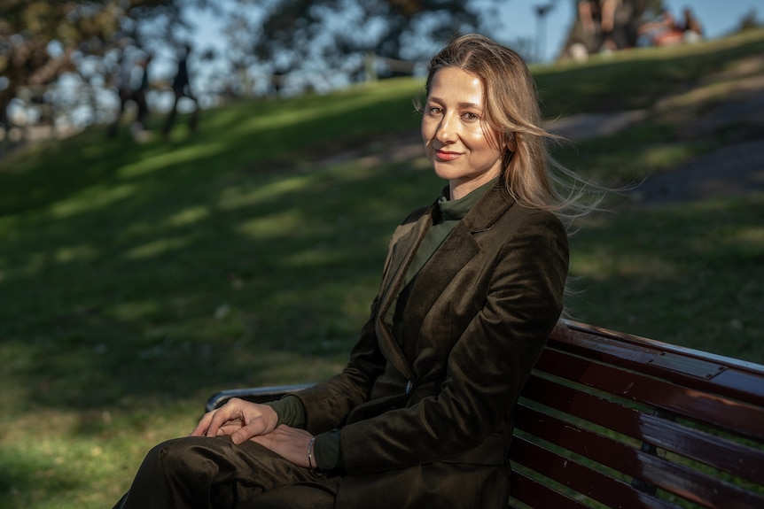 A woman sitting on a park bench, smiling.
