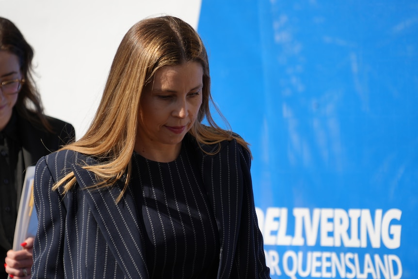 A woman wearing a striped jacket walking with her head down.