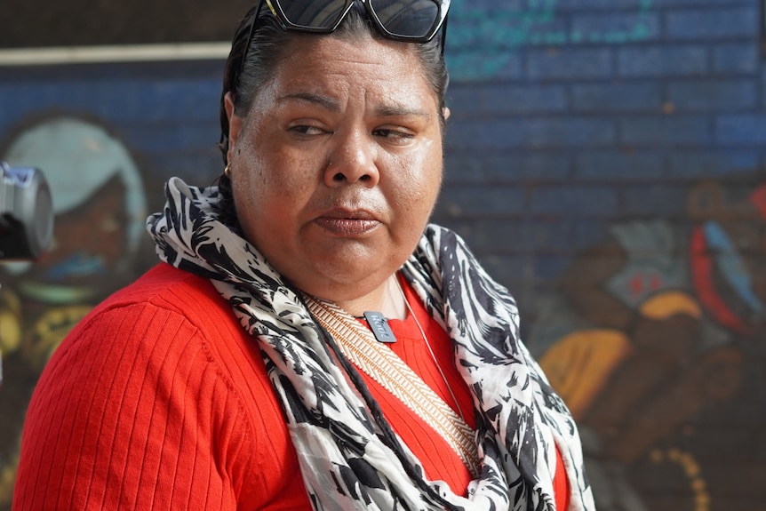 A woman wearing a red top and black and white scarf.