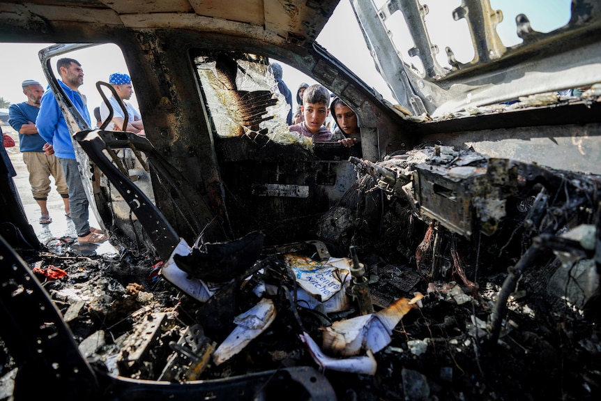People inspect the site where World Central Kitchen workers were killed by an Israeli drone strike
