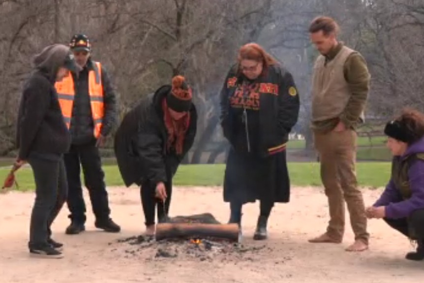 Several people gather around a fire at Camp Sovereignty.