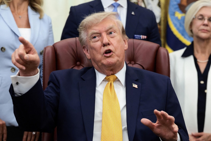 Trump points his finger as he talks to the media in the Oval Office.