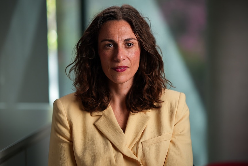 A woman with long dark hair with a serious expression on her face.