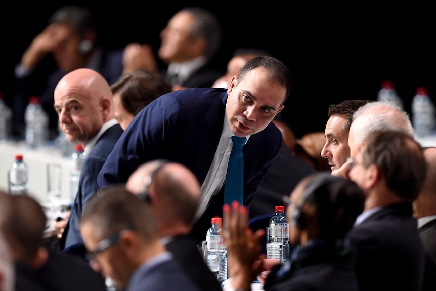 Men in suits at a sporting fixture