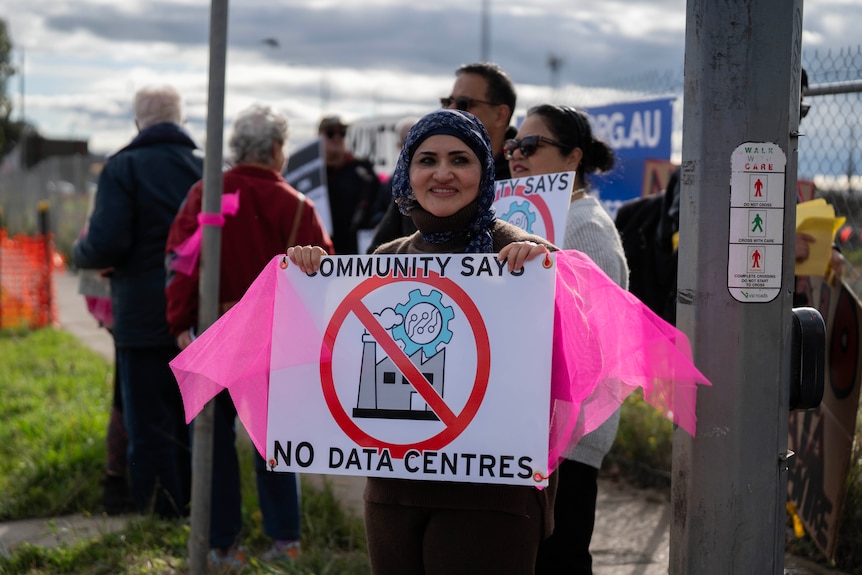 A woman holding a sign which reads: 'Community says no data centres.'