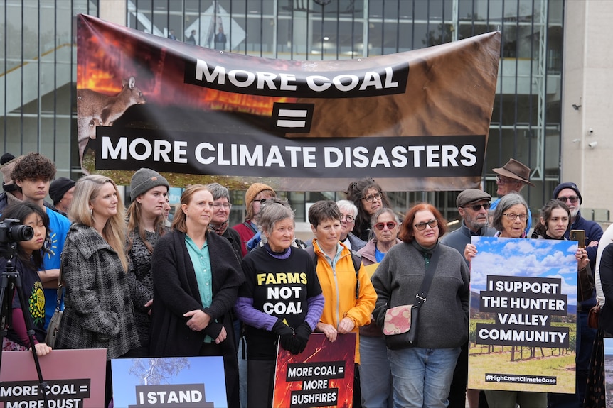 A crowd of women and a few men hold signs protesting coal mines in the Hunter Valley