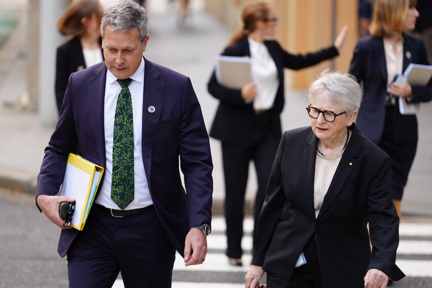 Man in suit with documents next to woman carring a bad