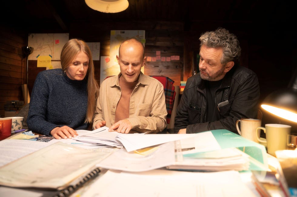 three people reviewing documents at a wooden table.