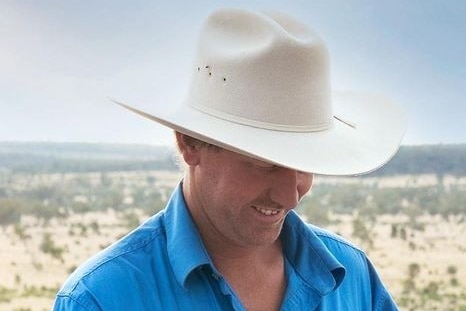 Graham holds his baby daughter with paddocks in the background.