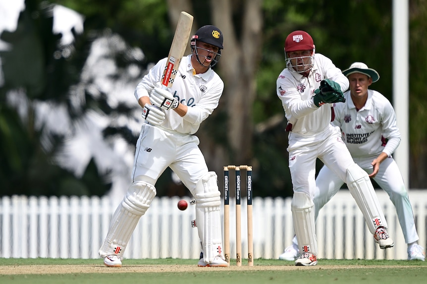 A man with a cricket bat tries to strike the ball which went through to the keeper