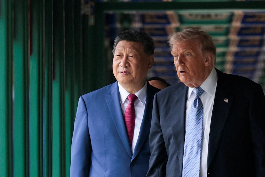 Trump and Xi, both wearing suits, look at something out of frame to the left