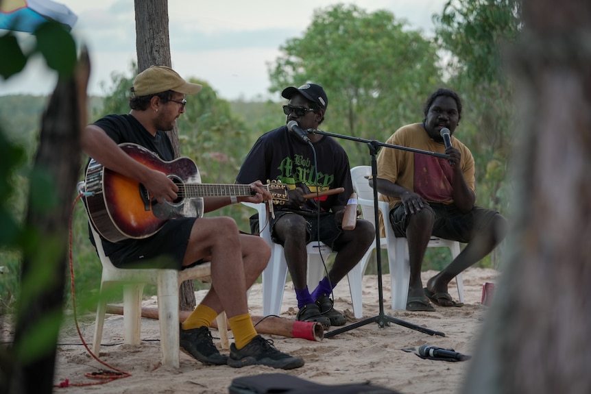 Three male members of a band perform while seated