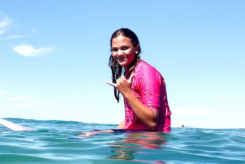A young woman sitting on a surfboard 