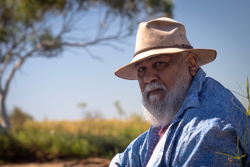 An Aboriginal man in his fifties wears a blue shirt and broad-brimmed hat.