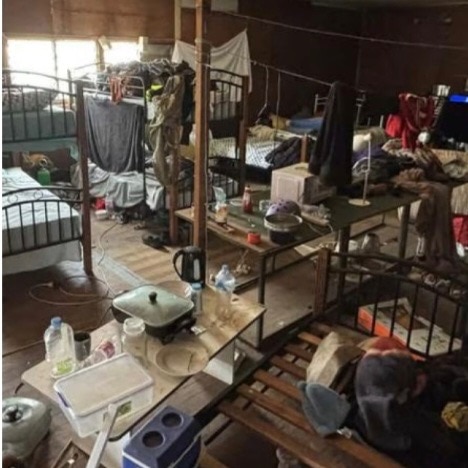 A large messy space showing several bunk beds.
