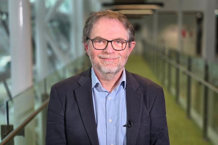 Professor Justin Zobel, computer scientist, looks at the camera smiling. He wears glasses and a black jacket