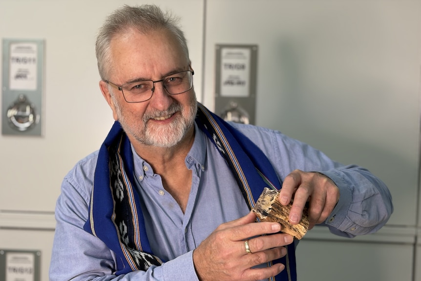 A man holding a small fossil