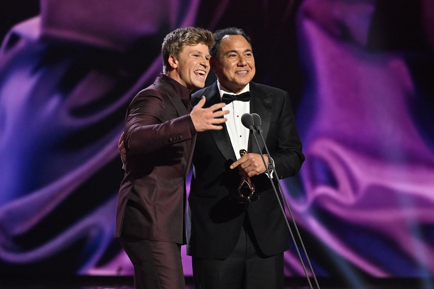Robert Irwin and Sam Pang stand in front of a microphone.