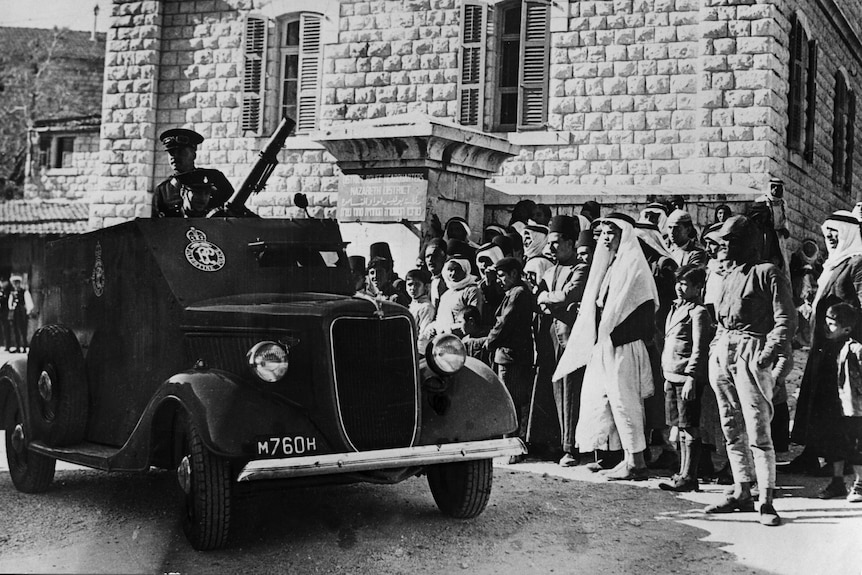 An armoured car of The British Palestine Mandate of the League of Nations drives past a crowd in Nazareth