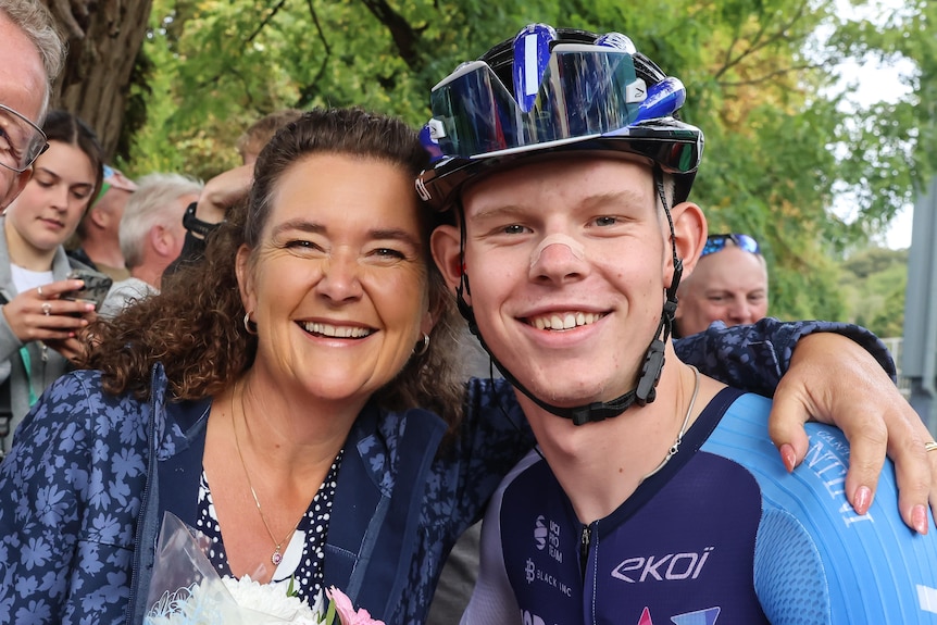 A cyclist smiles while hugging his mum.