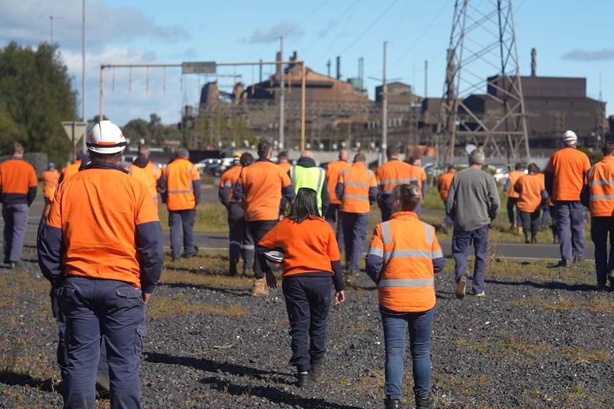 Workers walking towards an industrial smelter.