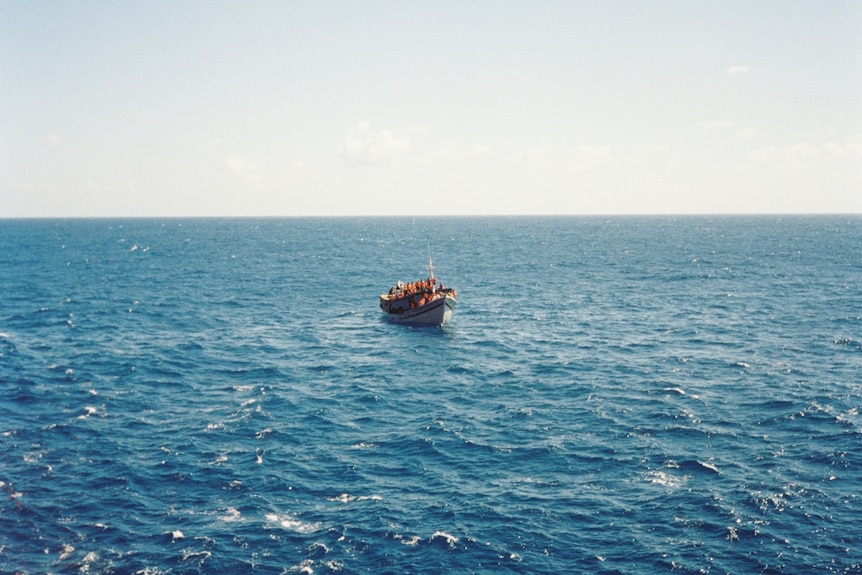 A small wooden boat bobs in the open ocean.