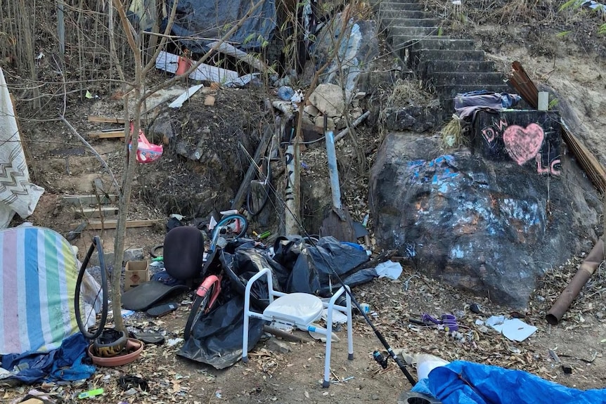 A photo of a camp site strewn with rubbish and belongings.