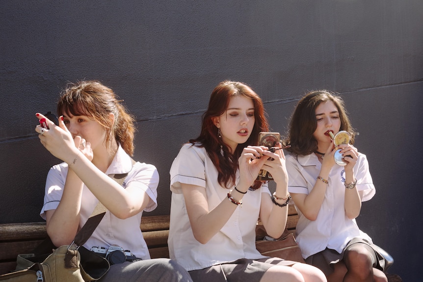 Three young women put on make-up 