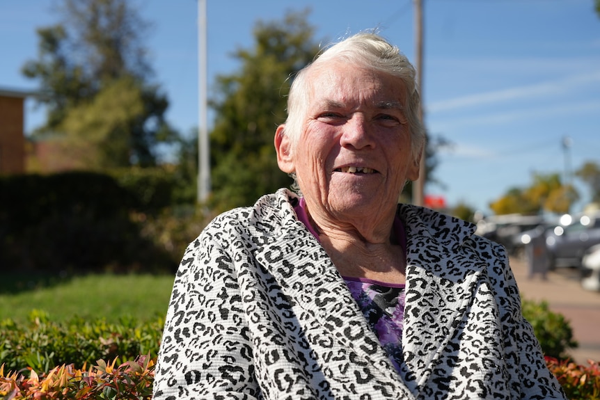 A woman sitting in a walker on the footpath of a country street