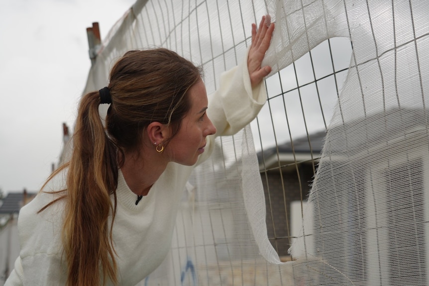 A woman peers into a housing site.