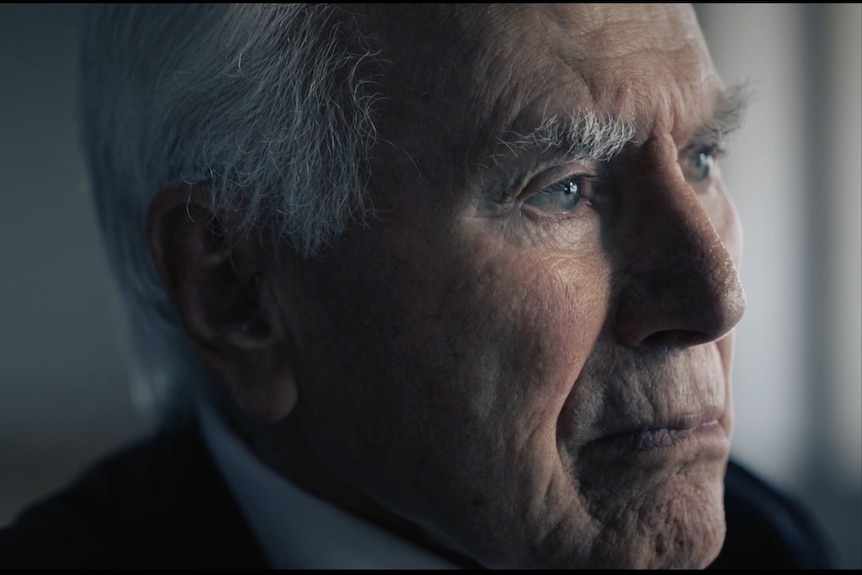 A close-up shot of an old man with thick white eyebrows looking thoughtfully off-camera.
