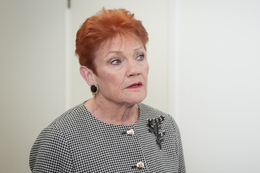 A woman with bright orange short hair, looking to the side with her mouth slightly ajar.